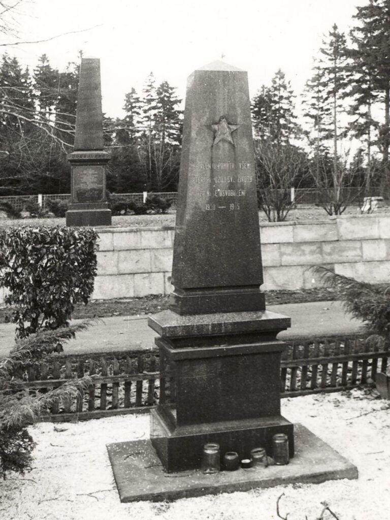 Předchozí pomníky odložené na hřbitově – v popředí pomník padlým z roku 1968 (doplněný o hvězdu), za ním německý válečný pomník z roku 1893 /Muzeum Aš