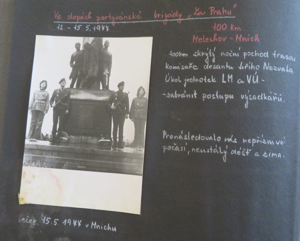 Pamětní tablo: Ve stopách partyzánské brigády „Za Prahu“ – v cíli nočního pochodu Melechov-Mnich s fotografií čestné stráže parašutistek Svazarmu u pomníku v Mnichu, 1977 /Obecní úřad Mnich