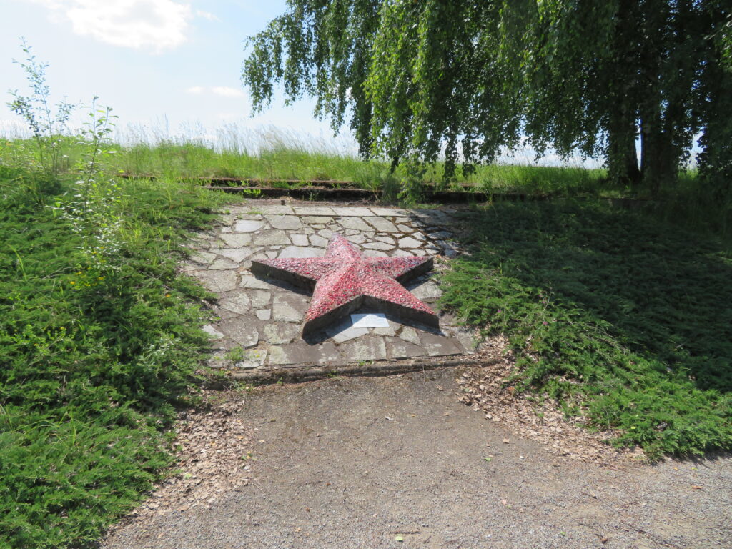 „Hvězda nad Mnichem“ - dochovaný a částečně rekonstruovaný reliéf pěticípé hvězdy ze střepů granátového skla pod bývalou tribunou, jeden z posledních pozůstatků předlistopadových velkolepých oslav v Mnichu /foto autorů červen 2025