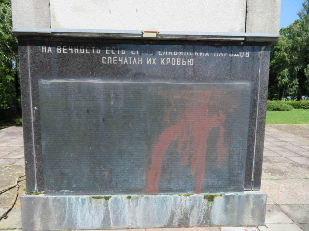 Žulová deska s ruským nápisem na boční stěně pomníku s viditelným postřikem červenou barvou, následek protestu po napadení Ukrajiny Ruskem v roce 2022 /foto autorů červen 2025