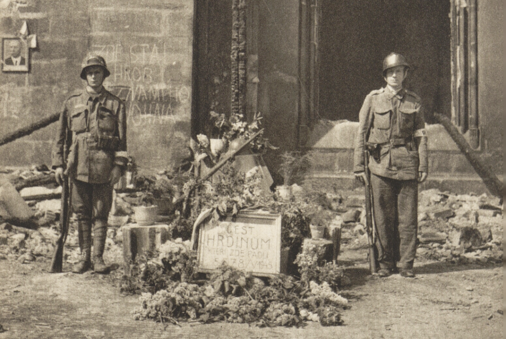 Bezprostřední snoubení dvou komemorací před Staroměstskou radnicí v květnu 1945 – improvizovaný pomník padlým v pražském povstání a připomínání zničeného hrobu Neznámého vojína z první světové války /foto z Památník pražského povstání 1945, 1946