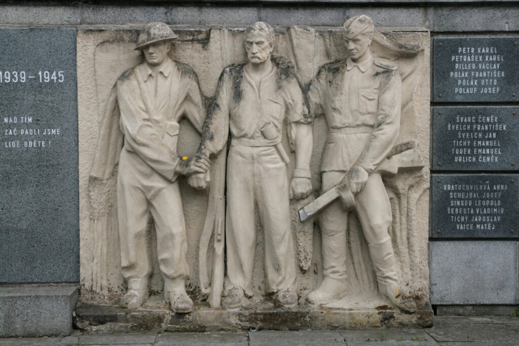 Sušice, Památník odbojů s reliéfem od Otakara Švece (1892–1955) znázorňujícím čs. zahraniční vojáky ze západu a východu s osvobozeným politickým vězněm. Opravený a doplněný památník z 30. let byl odhalen k 28. říjnu 1949 /foto Martin Strachoň, Wikimedia Commons, File:Sušice, nábřeží Jana Seitze, památník odboje (8132).jpg